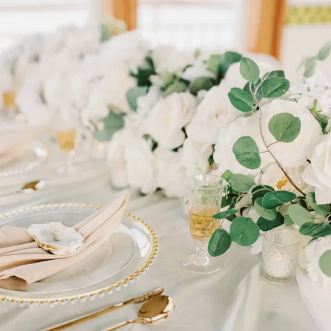 Elegant table setting with white flowers and gold cutlery.