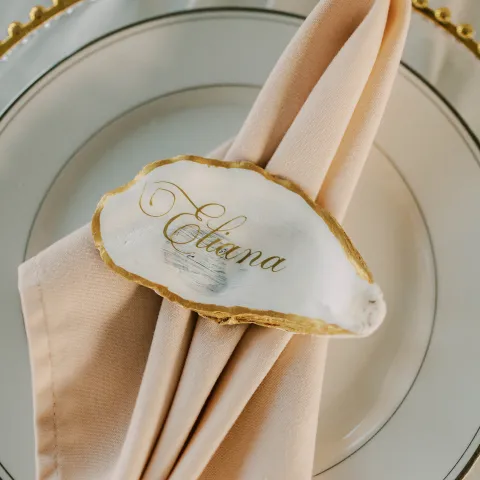 Elegant table setting with napkin, plate, and name tag on shell.