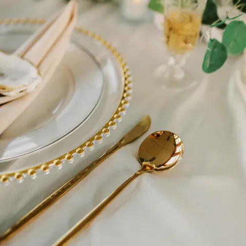 Elegant table setting with gold cutlery and decorative plates.