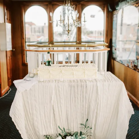 Elegant table setup with white tablecloth, chandelier above, and flowers below in a wood-paneled room.