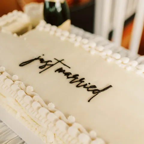 Rectangular cake with 'just married' on top, beside a champagne bottle.