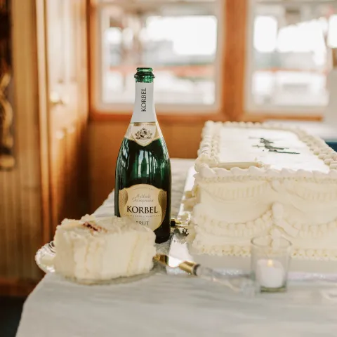 Champagne bottle beside an elegant white cake on a table.