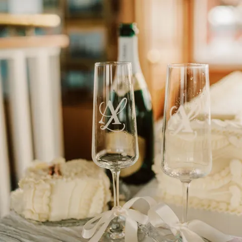 Two champagne flutes, a bottle, and a piece of cake on a table.