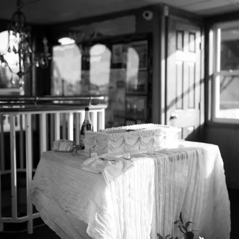 Table with a decorated cake and flower bouquet in a dimly lit room.