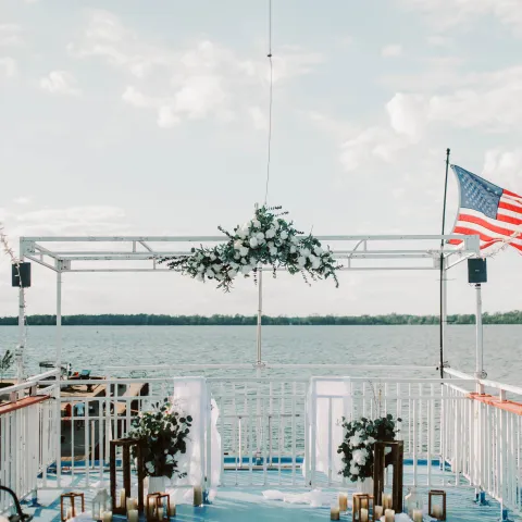 Outdoor wedding altar on a boat with an American flag and floral decoration.
