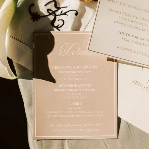 Wedding invitation and details card with rings and flowers.