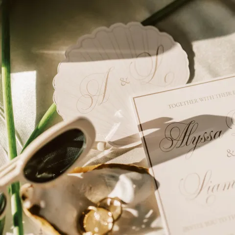 Wedding invitation with rings on shell, floral accents, and soft lighting.