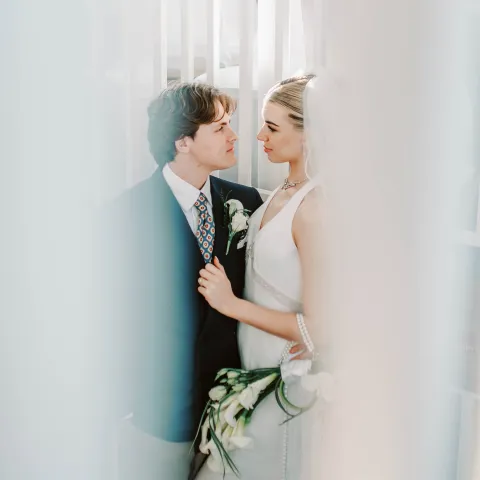 Bride and groom embracing on a staircase, holding flowers.