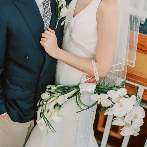 Bride and groom in elegant attire with white flowers.