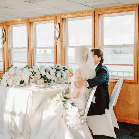 Bride and groom sitting at a decorated table on a boat.