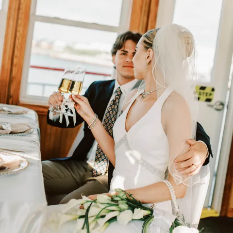Bride and groom sit together, toasting with champagne.