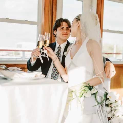 Bride and groom toasting with champagne indoors.
