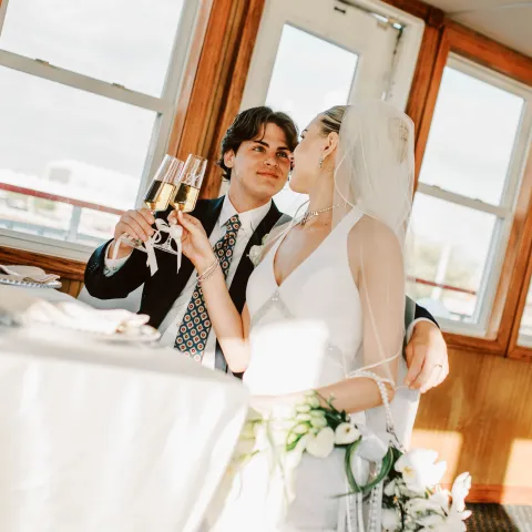 Bride and groom toasting with champagne in a sunny room.