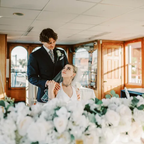 Bride and groom in a boat venue with floral decor in foreground.