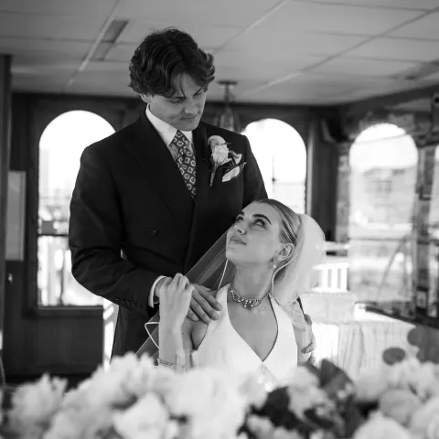 Bride and groom share a tender moment indoors, surrounded by flowers.