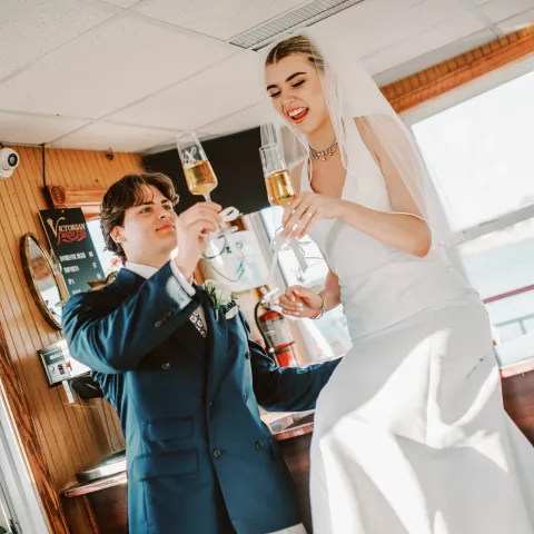 Bride and groom toasting with drinks in a bar setting.