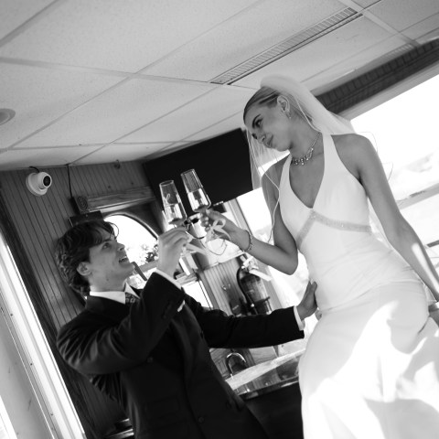 Bride and groom toasting with champagne on a boat.
