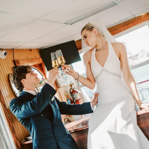 Bride and groom toasting with champagne on a boat.