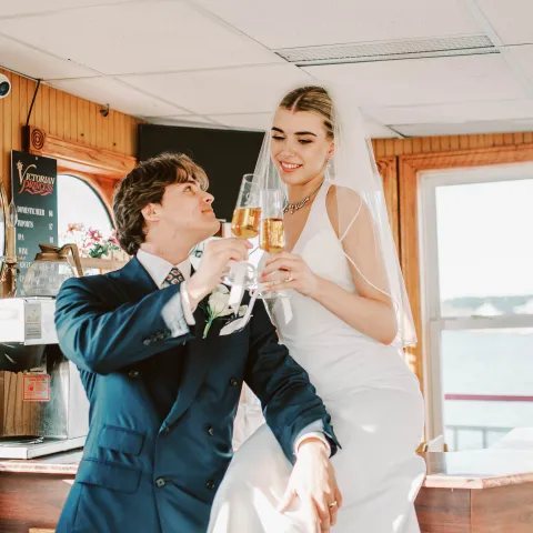 Bride and groom toasting with champagne on a boat.