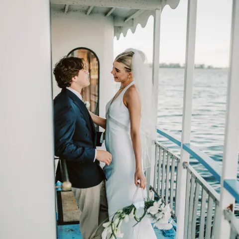 Bride and groom on boat deck with water view.