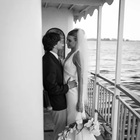 Bride and groom gazing at each other on a boat deck.