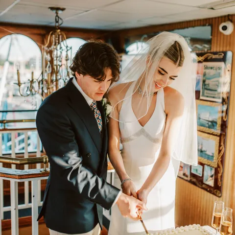 Bride and groom cutting a wedding cake on a boat.