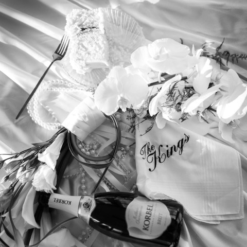 Champagne, flowers, napkin on satin with pearls and a fork.