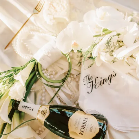 Champagne, flowers, and a napkin with 'The Kings' on satin fabric.