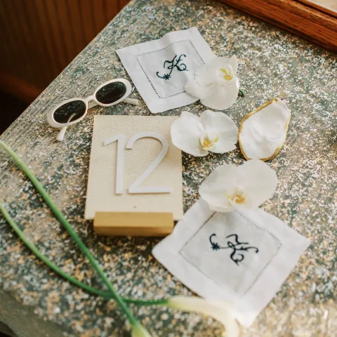 Table number 12, white flowers, sunglasses, and napkins on a stone countertop.