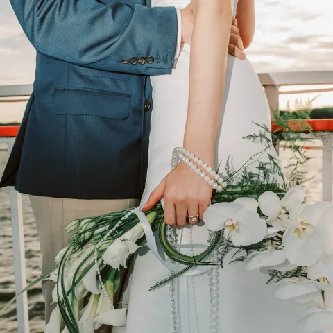 Couple embracing; bride holding bouquet of white flowers.
