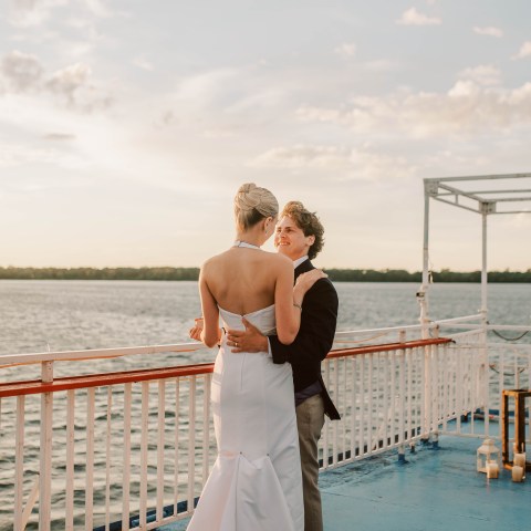 Couple dancing on a boat deck under a cloudy sky.