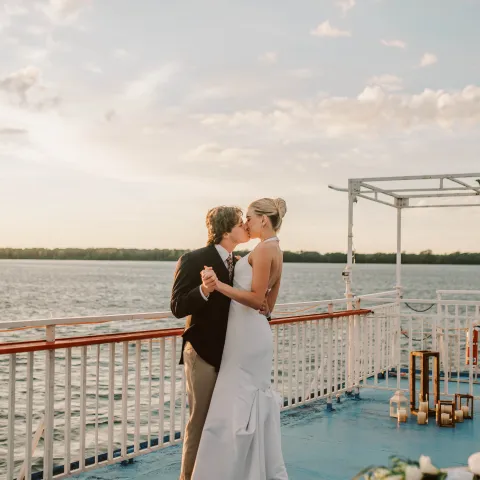 Couple dancing on a boat deck at sunset.