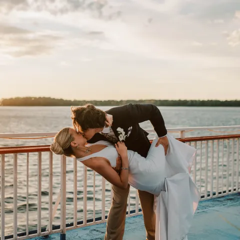 Couple kissing on a boat deck at sunset.