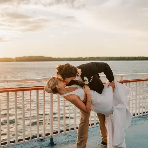 Couple dancing on a boat deck at sunset, man dips woman.