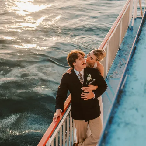 Couple embracing on a boat deck with ocean in the background.