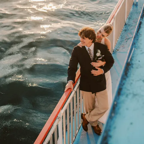 Couple embracing on a boat deck overlooking the water.