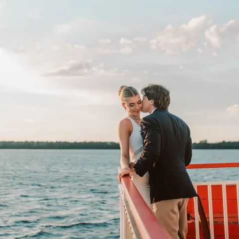 Couple embracing on a boat deck at sunset, near the railing.