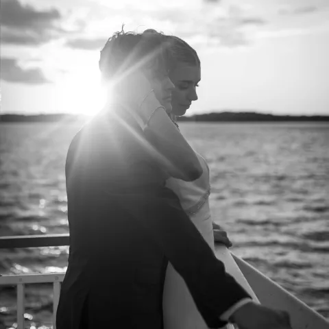 Couple embracing on a boat at sunset, black and white photo.