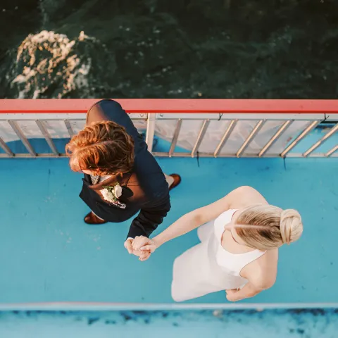 Top view of two people holding hands on a boat with blue flooring.