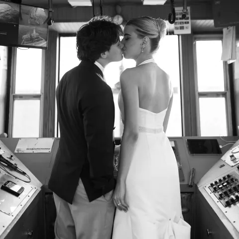 Couple in formal attire kissing in a ship's control room.