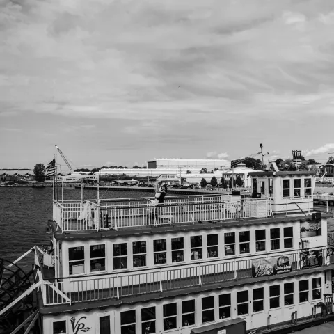 Black and white photo of a docked paddle steamer with three decks.