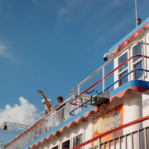 People on a colorful boat under a blue sky with banners displayed.