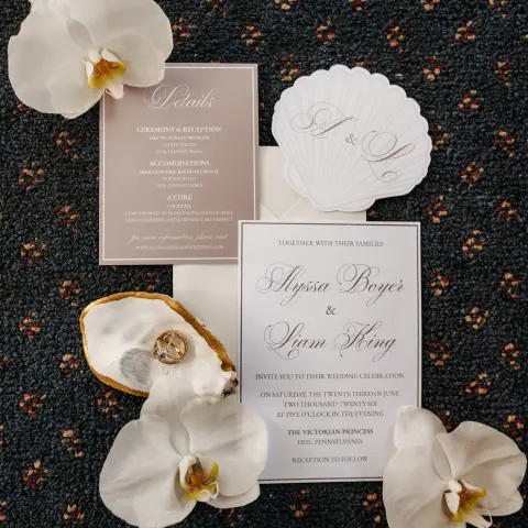 Wedding invitations with white orchids on patterned surface.