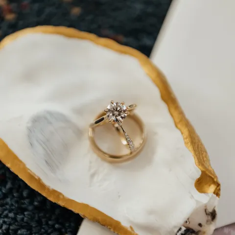 Gold ring with a diamond on a golden-edged oyster shell.