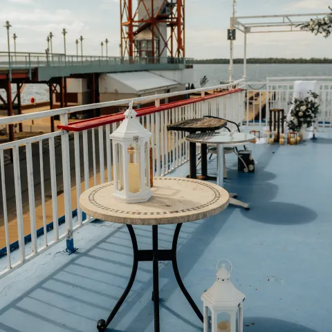 Outdoor deck with white lanterns on tables and distant tower view.