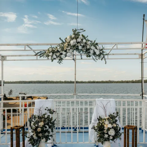Outdoor wedding setup with floral decorations by a lakeside.