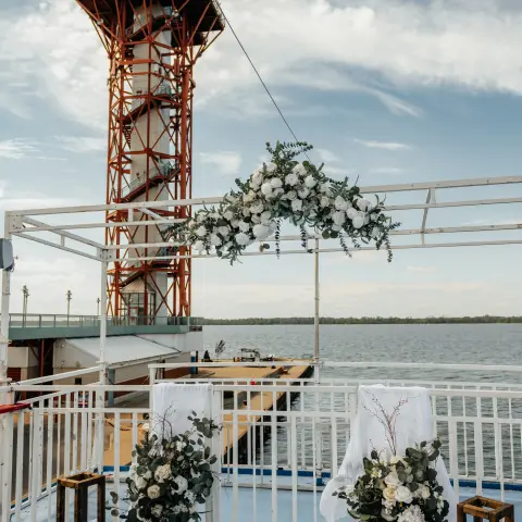 Lighthouse near decorated wedding altar with flowers and candles by the sea.