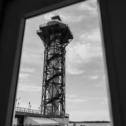 Tall tower by the water viewed through a window.