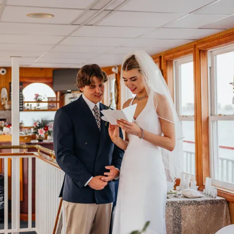 Bride and groom reading a letter together on a boat.