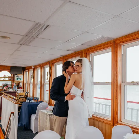 Bride and groom kissing inside a boat decorated for a wedding.